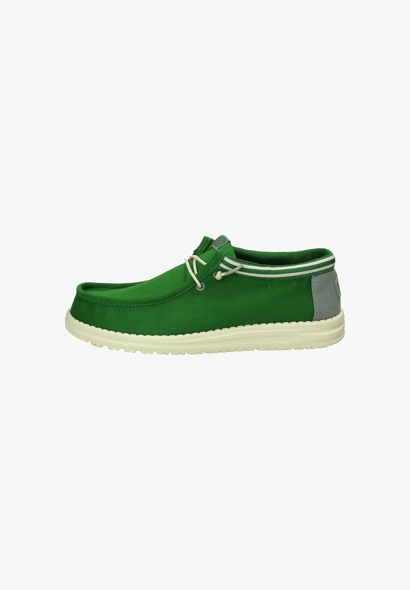 Scarpa slip-on verde in tela con accento grigio chiaro sul tallone, caratterizzata da una suola in gomma bianca e due dettagli decorativi a forma di lacci.