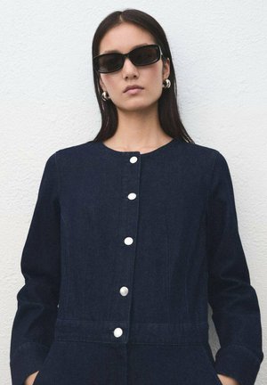 Robe en denim bleu marine avec un col rond, cinq boutons blancs sur le devant et des manches longues. Texture lisse et coupe ajustée.