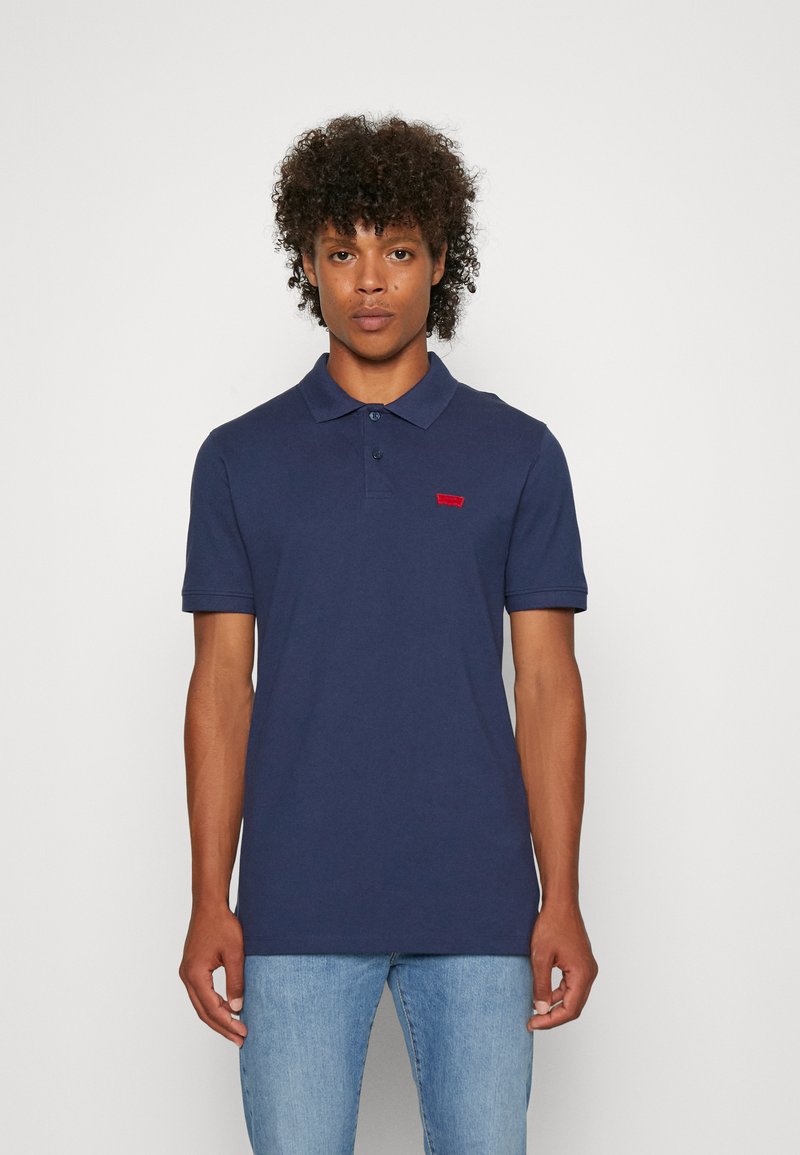 Polo shirt navy in cotone, con colletto con bottoni, maniche corte e un piccolo logo rosso sul lato sinistro.