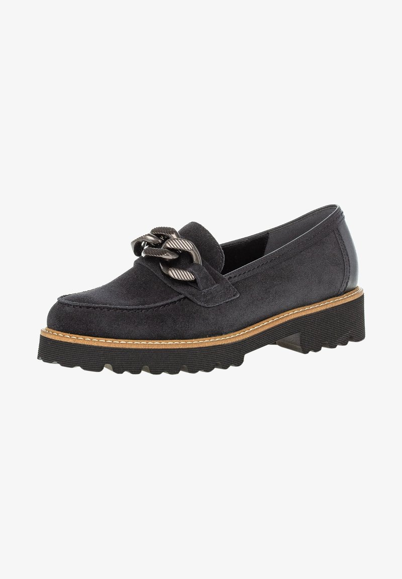 Mocassin en daim noir avec semelle épaisse en caoutchouc, coutures brunes claires et un grand détail en chaîne métallique texturée sur le dessus.