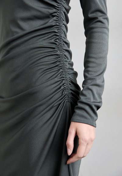 Dark gray dress featuring ruched texture along the side, long sleeves, and a fitted silhouette with smooth fabric.