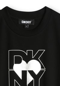 Czarna bawełniana koszulka z dużym, srebrnym logo DKNY, w które wkomponowano kształt serca. Okrągły dekolt i krótkie rękawy.