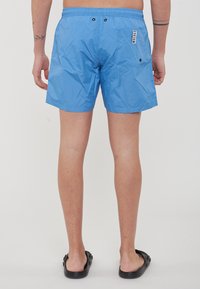 Pantaloni da bagno blu realizzati in materiale leggero, con vita elastica, due tasche posteriori e caratteristiche hardware nere.