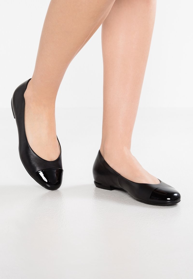 Ballerine in pelle nera con punta in vernice nera lucida e corpo opaco, dotate di un tacco basso per comfort e facilità d'uso.