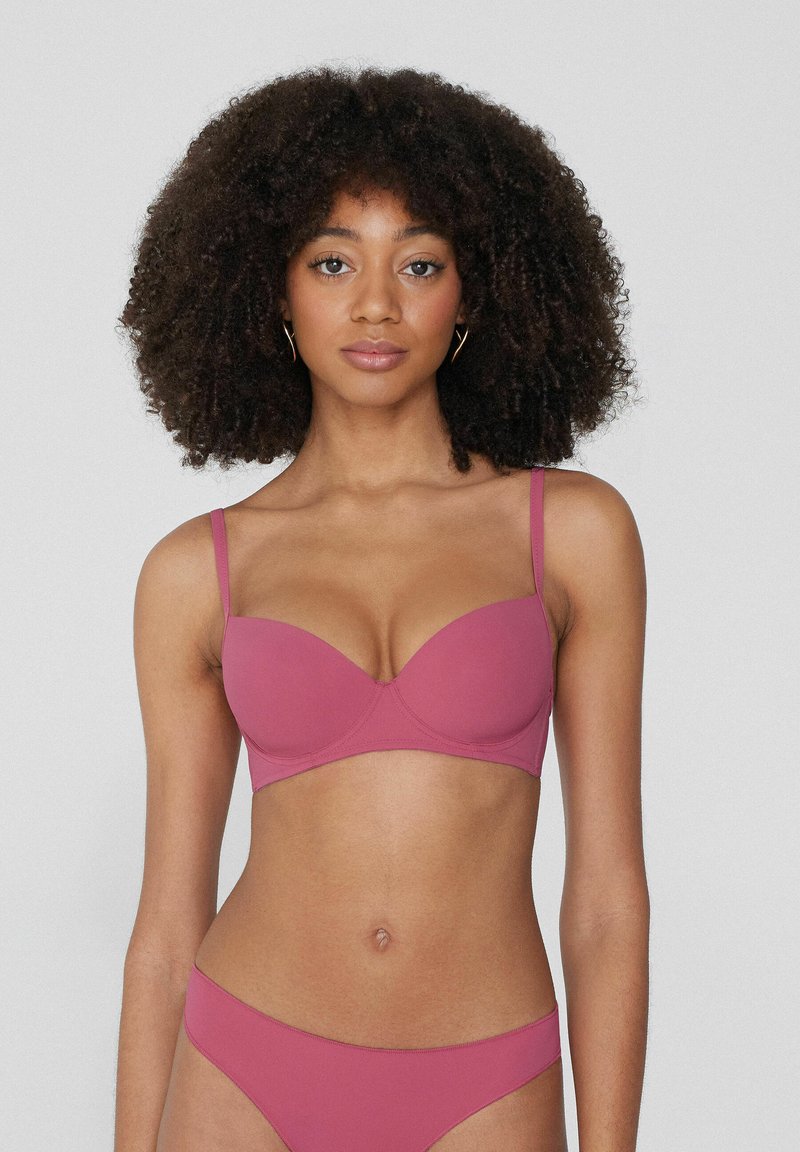 Formovaný podprsenka v jednobarevné maliny s tenkými nastavitelnými ramínky. Hladký povrch a podpora s kosticemi, vybavená bezešvým designem.