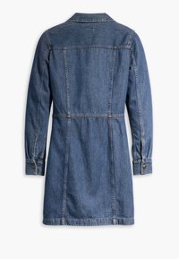 Denimmekko, jossa on pitkät hihat, vaaleansininen väri, nappikämmenet ja ommellut saumat. Suunnittelussa on muotoiltu vyötärö ja takaosa yksityiskohtana.
