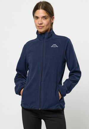Navy fleece-takki korkealla kauluksella, täysivetoketjulla, sivutaskuilla ja Kappa-logolla rinnassa. Pehmeä tekstuuri, vartalonmyötäinen muotoilu tummilla yksityiskohdilla.