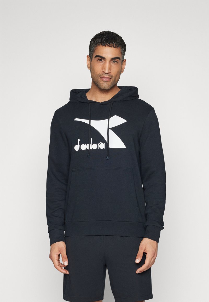 Felpa nera con cappuccio e logo Diadora bianco. Presenta una tasca a kangaroo e polsini a costine; realizzata in un tessuto morbido e testurizzato.