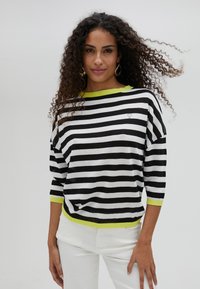 Striped black and white sweater with a lime green collar and cuffs, featuring a loose fit and three-quarter sleeves. Small heart logo detail.
