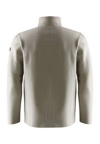 Beige jacka med hög krage, textil med struktur, och kontrasterande släta axelpatchar. Har en andningsbar meshnätpanel på ryggen.