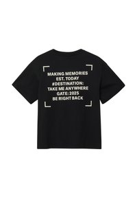 Zwart katoenen T-shirt met witte tekst op de achterkant, met reisgerelateerde zinnen en een box-accentontwerp. Losse pasvorm, korte mouwen.