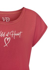 Červené bavlnené tričko s okrúhlym výstrihom a krátkymi rukávmi, s bielym rukopisným textom "Divoký v srdci" a jednoduchým dizajnom srdca.