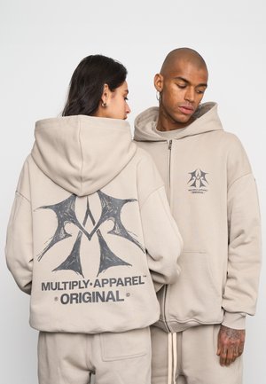 Sudaderas de color hueso con un gran gráfico negro en la parte posterior y un logotipo más pequeño en la parte delantera. Fabricadas en algodón suave y texturizado, con un ajuste relajado.