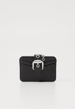 Black faux leather cardholder with a buckle flap, silver hardware, textured surface, and decorative charm. Compact rectangular shape.