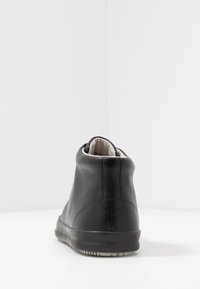 Black leather high-top sneaker with smooth texture, contrasting white lining, and rubber sole featuring distinct tread pattern.
