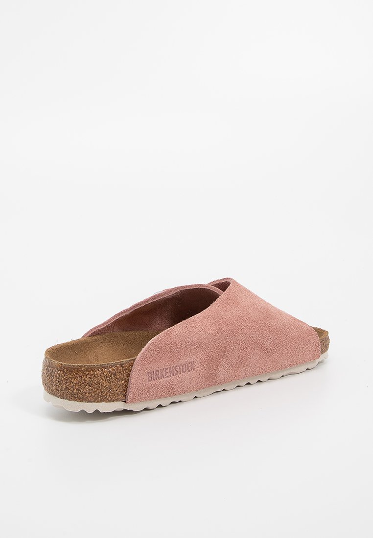 Rosa Wildleder-Slipper mit einem Korkfußbett und einer strukturierten Gummi-Laufsohle. Verfügt über eine breite Öffnung und ein dezentes eingeprägtes Logo an der Seite.