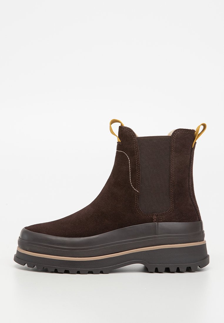 Bruna mockaskinnankelboots med elastiska sidopaneler, en kontrasterande brun gummisul med dragflik för enkelt påtagande. Texturerad finish.