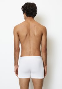 Boxer da uomo in cotone elastico bianco con una vita morbida che mostra il nome del marchio. Texture liscia e design aderente, posizionati su uno sfondo solido.