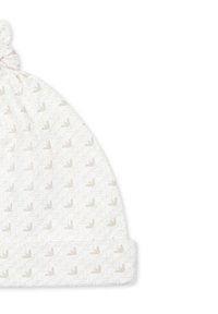 Knotmuts voor baby's van witte stof, met een subtiel geometrisch patroon in beige. Zachte textuur met een omgeslagen boord aan de onderkant.