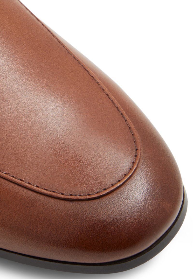 Empeigne en cuir marron avec une texture lisse, bout arrondi et couture détaillée autour des coutures et du bord. Semelle noire incluse.