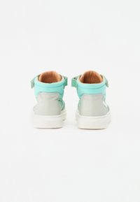 Zapatillas altas en verde menta con acentos grises, con una correa de velcro y un cuello acolchado, materiales de cuero texturizado y malla.