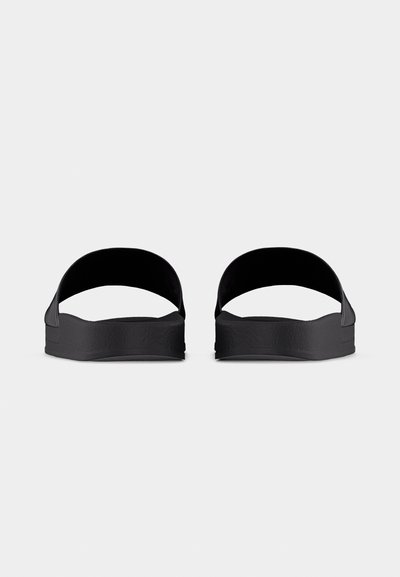 Ζευγάρι μαύρα σανδάλια τύπου slide με χοντρές σόλες και φαρδιές λουράκια, εμφανιζόμενα από μπροστά σε απλό φωτεινό φόντο.