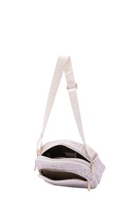 Borsa a spalla bianca in tela con motivo a logo in rilievo, scompartimenti con zip, hardware dorato e tracolla regolabile. Superficie texturizzata.