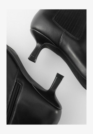 Svarta läderankelstövlar med en smal klack, med en sidodragkedja och elastisk panel för passform. Slät textur och minimalistisk design.