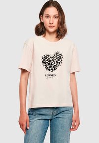 Roosa puuvillane T-särk musta leopardi prindiga süda kujundusega, mille all on tekst "LEOPARD Heart", lühikesed varrukad ja mugav lõige.