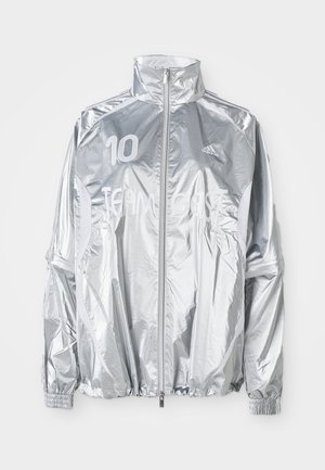Zilveren Adidas zip-up jack met hoge kraag, elastische manchetten, "10" op de linkerborst en de tekst "TEAM GAST" over de voorkant.