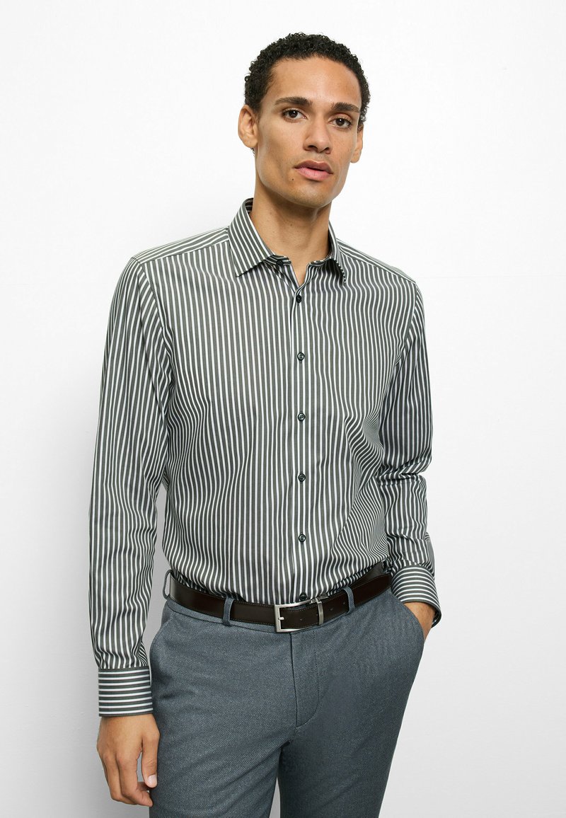 Men's button-up shirt with vertical gray and white stripes, sleek collar, and single chest pocket; paired with textured blue trousers.