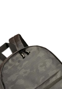 Grijze camouflage rugzak met twee gevoerde schouderbanden, gladde textuur en ritsluiting; merketiketten aan de bovenkant.