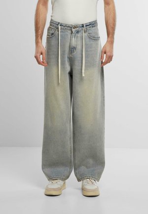 Jeans in denim chiaro con vestibilità ampia, vita con coulisse e lievi sgualciture. Caratterizzati da un design a cinque tasche e chiusura con bottone frontale.