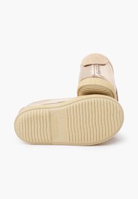 Zlatavý kovový boty s jemnými semišovými akcenty, zaoblenou špičkou a texturovanou gumovou podrážkou s ryhovanými vzory a potiskem.