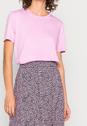 Jasnoróżowy bawełniany t-shirt z krótkim rękawem, zestawiony z czarną spódnicą w białe kwiatowe wzory i marszczonym pasem.