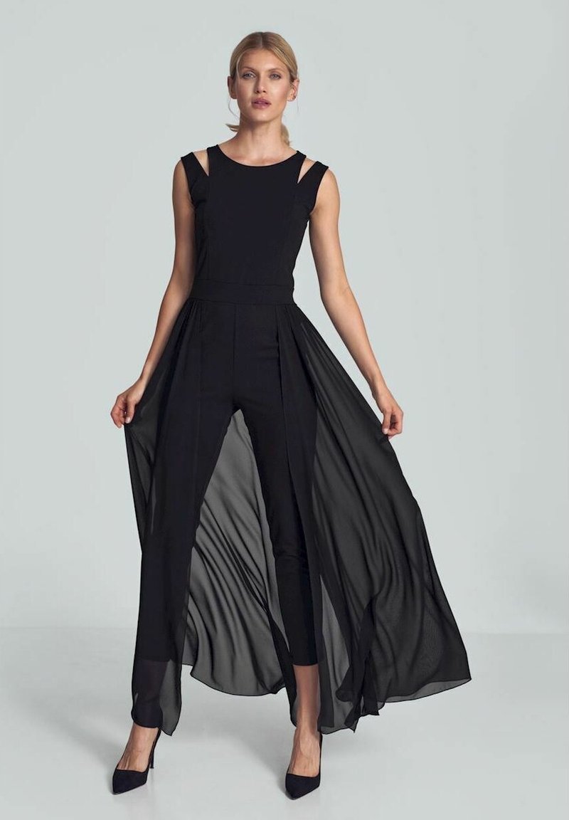 Zwarte jumpsuit met transparante, vloeiende overlay. Bevat schouderuitsnijdingen, een getailleerde buste en een uitlopende onderkant. Gladde textuur en elegante lijnen.