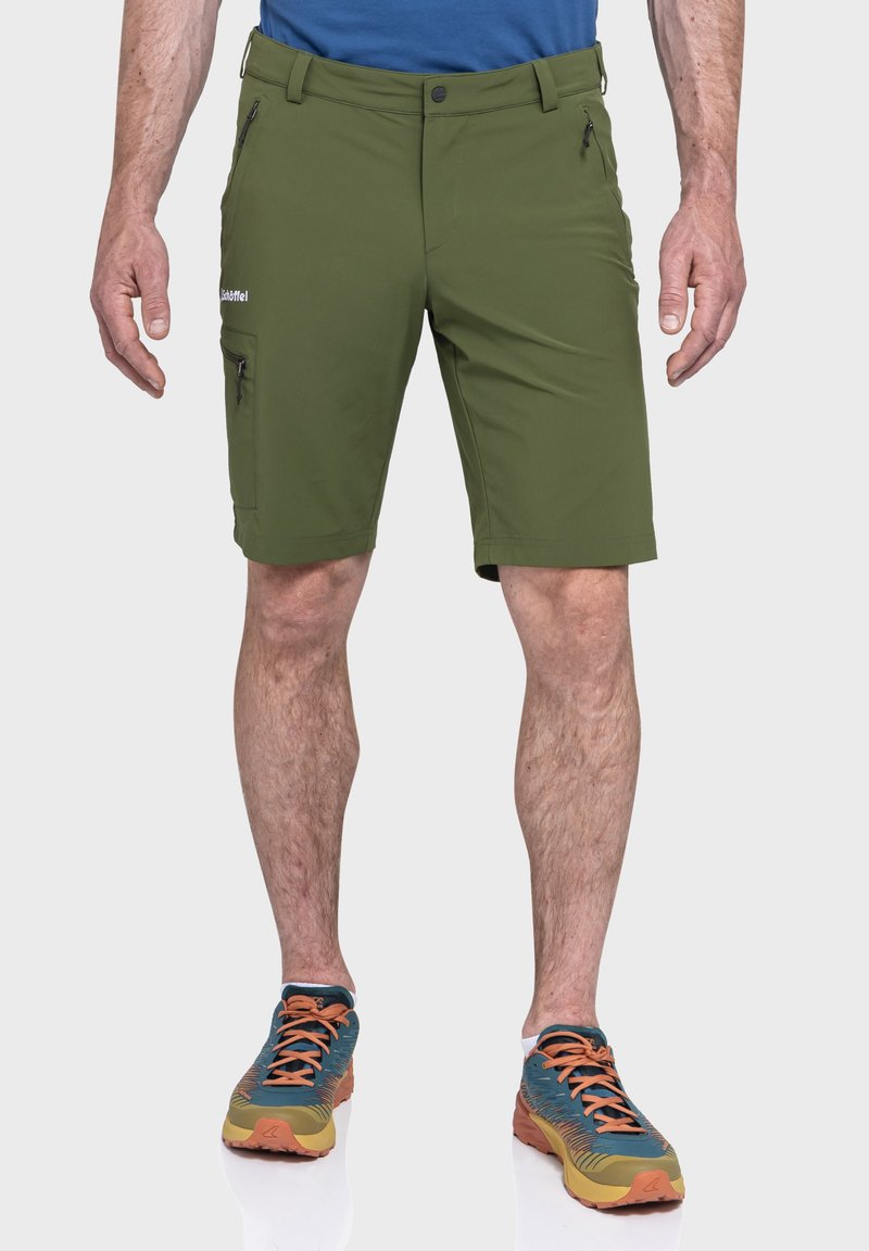 Grüne Sportshorts mit einer glatten, matten Oberfläche, Reißverschlusstaschen an den Seiten und einer taillierten Passform. Kombiniert mit mehrfarbigen Sportschuhen.