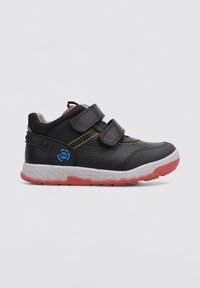 Chaussures en cuir noir avec deux bandes Velcro, coutures jaunes, accents bleus, un talon noir texturé et une semelle en caoutchouc rouge et blanc.