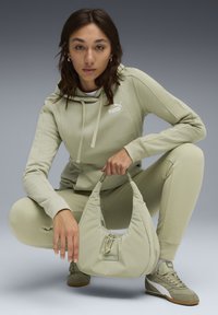Lys grøn oversized hoodie med snoretræk og logo, matchende bukser og en blød, tekstureret håndtaske med samlet top og accent hardware.