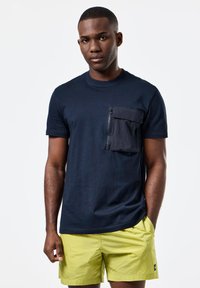 Tricou de culoare bleu marin, cu mânecă scurtă, prevăzut cu un buzunar cu fermoar pe pieptul stâng, asortat cu pantaloni scurți de culoare verde lime. Material neted, croială lejeră.