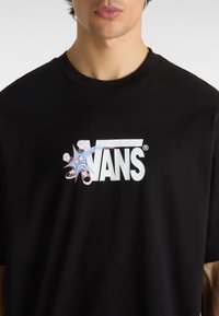 Black cotton t-shirt featuring a white "VANS" logo and colorful graphic with fists and shoes, round neck, and short sleeves.