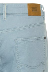 Jasnoniebieskie szorty dżinsowe z brązową skórzaną naszywką marki. Posiadają standardowy design kieszeni i kontrastujące przeszycia.
