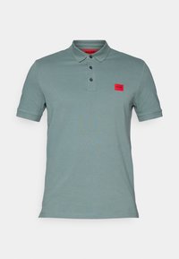 Polo vert clair à manches courtes avec col, trois boutons noirs et un petit écusson logo Hugo rouge sur la poitrine gauche.