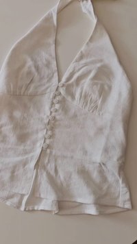 White halter top with a textured fabric, featuring a fitted bodice, gathered bust, and a button closure down the front.