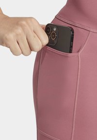 Højtaljede, mørkeblå træningsleggings i pink med en yderlomme til en smartphone, lavet af glat, strækbart stof.