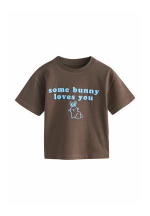 Brown short-sleeve t-shirt with light blue text "some bunny loves you" and a simple blue bunny illustration below the text.