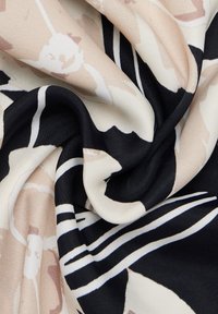 Écharpe en soie avec un motif floral beige et blanc sur fond noir, ornée de rayures blanches contrastantes ; texture lisse.