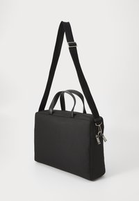 Sac à ordinateur portable en tissu noir avec double poignées supérieures, bandoulière réglable, accents en matériel argenté et une forme rectangulaire simple.