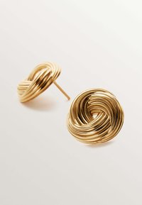 Pendientes de stud en tono dorado, hechos de metal, con un diseño retorcido que presenta líneas suaves y curvas, y un acabado pulido.