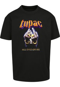Svart bomull T-skjorte med et grafisk bilde av en person med utstrakte hender, omgitt av teksten "tupac" og "ALL EYEZ ON ME" i sterke farger.